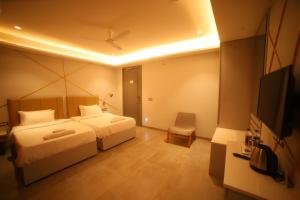 a bedroom with two beds and a flat screen tv at Waltair Abode in Visakhapatnam