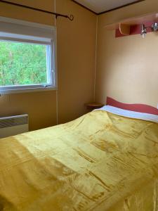 - une chambre avec un grand lit et une fenêtre dans l'établissement Camping de la ferme aux ânesses, mobil home myrtille, à Bressuire