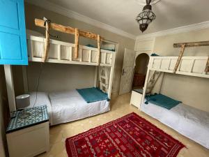 een slaapkamer met 2 stapelbedden en een rood tapijt bij Taghazout Ocean View in Taghazout