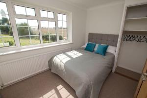 a bedroom with a bed with blue pillows on it at Spacious 5 bed in the countryside, close to Frinton-On-Sea in Kirby Cross