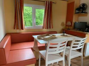 sala de estar con mesa y sofá rojo en Camping de la ferme au ânesses, mobil home happy, en Bressuire