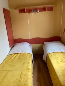 two beds sitting next to each other in a room at Camping de la ferme au ânesses, mobil home happy in Bressuire