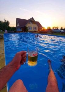 a man holding a glass of beer in a swimming pool at La Cabană Girov in Girov