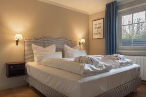 a bedroom with a bed with white sheets and pillows at Mimosa House in Westerland