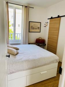 - une chambre avec un lit blanc et une fenêtre dans l'établissement CLINT HOUSE - Appartement "l'Île aux Moines", à Perros-Guirec