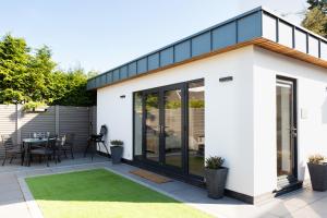 a contemporary extension to a home with a patio and grass at Dafarn Newydd Lodge in Llangefni