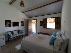 a bedroom with a large bed and a couch at Pousada Pedra do Negro in Caraíva