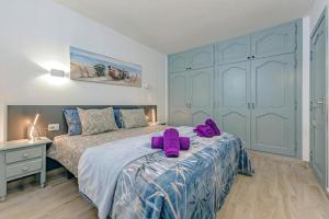 sypialnia z 2 fioletowymi ręcznikami na łóżku w obiekcie Neptuno Oceanview Suite with pool and beach private access w mieście Puerto de Santiago
