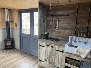 a kitchen with wooden walls and a stove and a door at Fairwood Lakes Holiday Park in Westbury