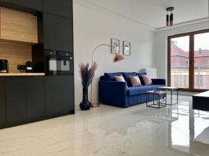 Il comprend un salon avec un canapé bleu et une cuisine. dans l'établissement Apartament Charlotte Link, à Jelenia Góra