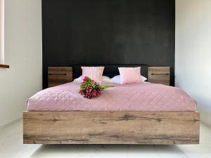 - un lit avec une couverture rose et un bouquet de fleurs dans l'établissement Apartament Charlotte Link, à Jelenia Góra