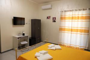 a room with a yellow table and a television at Appartamento Alla Marmora Porto Empedocle in Porto Empedocle
