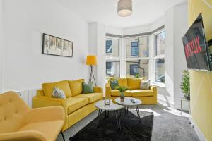 a living room with two yellow couches and a table at Luxe Holiday Apartments by Sasco in Blackpool