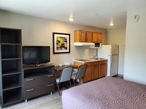 a small room with a bed and a kitchen with a television at WoodSpring Suites Raleigh Apex in Apex