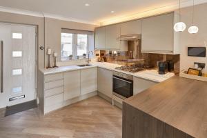 a kitchen with white cabinets and a wooden floor at Host & Stay - Priory Yard, Barnard Castle in Barnard Castle
