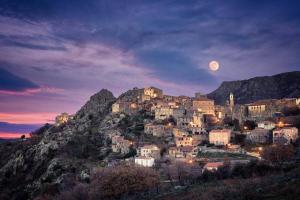 a town on a hill at night with the moon at A Spelunca in Speloncato