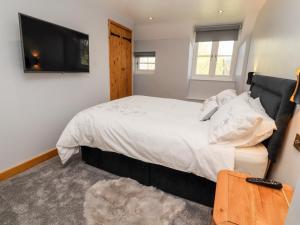 a bedroom with a large bed and a flat screen tv at Nant Y Celyn in Ruthin