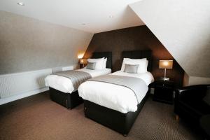 a hotel room with two beds and a chair at New Inn Hotel in Ellon