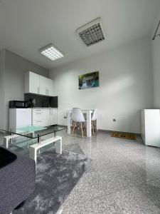 a living room with a glass table and a kitchen at Apartman Nikolic 2 in Teslić