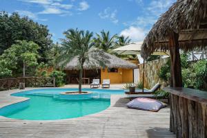a swimming pool in a resort with a palm tree at Pousada Rota dos Ventos in Barra Grande