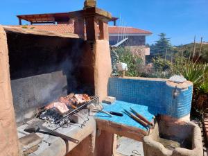 an outdoor grill with meat cooking on top of it at Rúnkina in Monte Petrosu