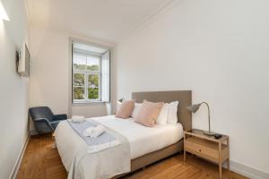 een witte slaapkamer met een bed en een raam bij Beautiful Apartment close to Praça do Comércio by LovelyStay in Lissabon