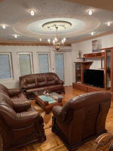 a living room with leather furniture and a flat screen tv at Apartment Alpi in Peje