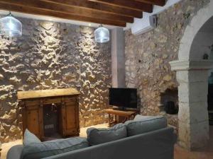 a living room with a stone wall with a couch and a television at Town House Ca Na Mabel in Sa Pobla in Sa Pobla