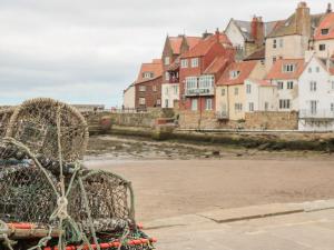 a chair sitting on the beach with houses in the background at Ashben Cottage in Whitby