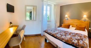 a bedroom with a bed and a desk and a table at Hôtel Le Troubadour à Rocamadour in Rocamadour