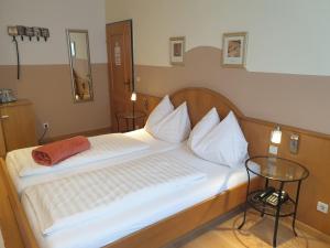 a bedroom with a large white bed with a wooden headboard at Hotel Pension Alte Mühle in Klosterneuburg