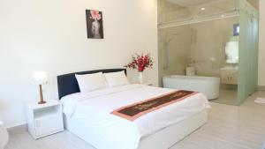 a bedroom with a white bed and a bath tub at Green Star Premium Resort - Mui Ne - Formerly Hung Thinh Resort in Ấp Long Sơn