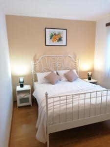 1 dormitorio con 1 cama blanca y 2 mesitas de noche en Apartment Mari, en Funtana