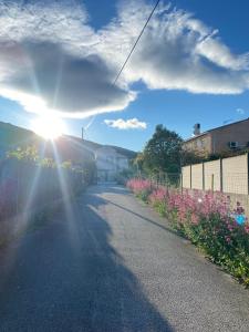 a sun shining down a road with flowers and a fence at Villa Pierre et Mer, maison 6 personnes a deux pas des plages in Hyères