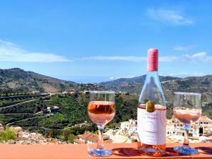 una bottiglia di vino e due bicchieri su un cornicione di Casa TRIGO a Cómpeta