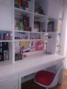una scrivania bianca con sedia rossa e librerie di Lindo monoambiente a Buenos Aires