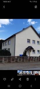 a white house with a fence in front of it at Ferienwohnung Günther am Park in Ditfurt