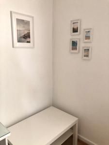 une chambre blanche avec une table et trois photos sur le mur dans l'établissement Arcada House Tavira, à Tavira