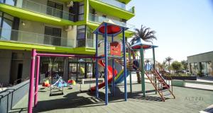a playground in front of a building with play equipment at Alezzi Beach Resort - Sea View Suite in Mamaia Nord