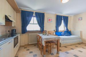 eine Küche mit einem Tisch und einem Bett mit blauen Vorhängen in der Unterkunft Chalet Li Baita Daniela in Livigno