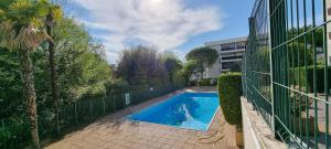 une piscine avec une clôture à côté d'un bâtiment dans l'établissement HOME ET HOLIDAY Le Petit Manseng, à Nice