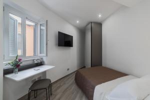 een slaapkamer met een bed, een bureau en een televisie bij B&B Piazza Roma in Norma