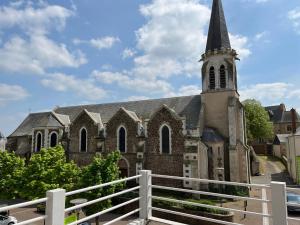 una iglesia con campanario y valla blanca en Appart'hôtel La Suze sur Sarthe, en La Suze-sur-Sarthe