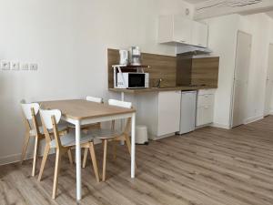 cocina y comedor con mesa y sillas en Appart'hôtel La Suze sur Sarthe, en La Suze-sur-Sarthe