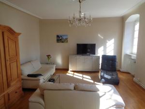 ein Wohnzimmer mit einem weißen Sofa und einem Fernseher in der Unterkunft Ferienwohnung Altes Pfarrhaus mit Flair und Moselblick in Brauneberg