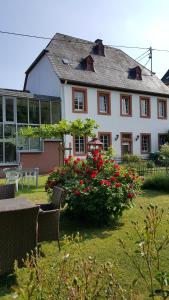 una casa blanca con flores rojas en un patio en Ferienwohnung Brauneberger Juffer im Alten Pfarrhaus, en Brauneberg