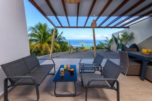 eine Terrasse mit Stühlen, einem Tisch und Meerblick in der Unterkunft DHM - Domaine Habitation Merveilleuse in La Trinité