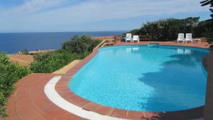 duży basen z krzesłami i oceanem w obiekcie Casa Mira con piscina e bellissima vista mare w mieście Costa Paradiso