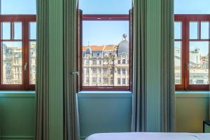 Schlafzimmer mit einem Fenster mit Blick auf ein Gebäude in der Unterkunft The Editory Boulevard Aliados Hotel - Preferred Hotels in Porto