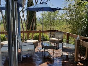 a patio with chairs and an umbrella on a porch at Adorable chalet avec jacuzzi privatif in Aix-en-Provence